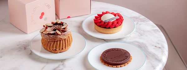 Three cakes on a table, with takeaway boxes next to them.