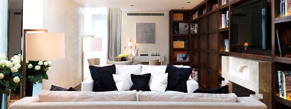 The Library Suite at The Connaught - Lounge view with couch, dining area in the background and library on the right hand side.