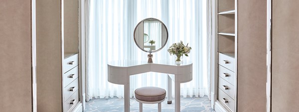 The walk-in wardrobe at The Apartment at The Connaught with a makeup table and a mirror on it.